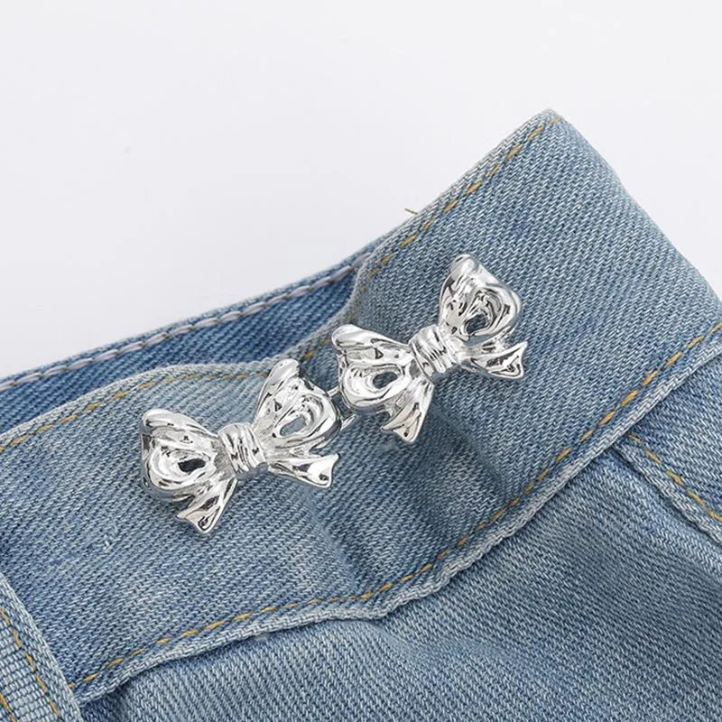 Silver bow-shaped brooches clipped onto a blue denim fabric
