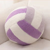 A plush volleyball ball cushion with white and purple stripes resting on a white surface.