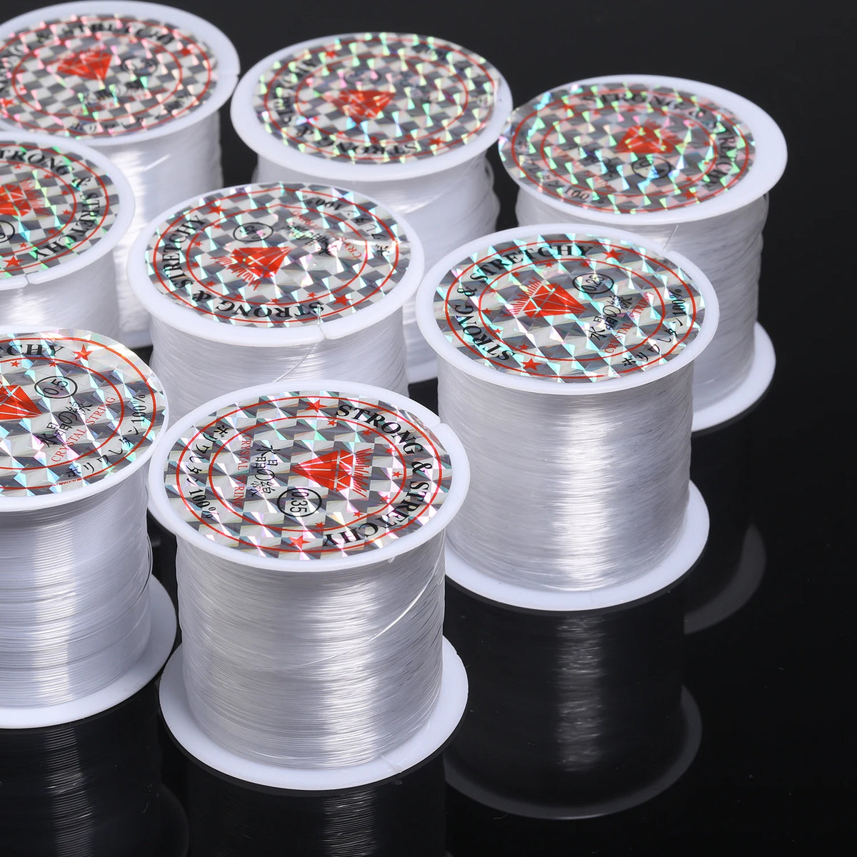 Rolls of precision nylon beading thread for jewelry making stacked on a dark surface