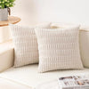 A set of two cream-colored, textured knit throw pillow covers resting on a white surface.