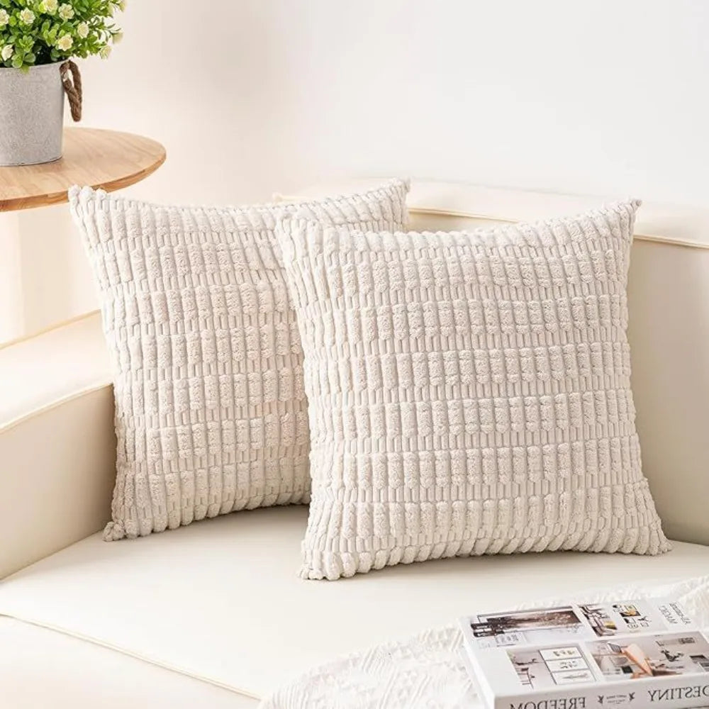 A set of two cream-colored, textured knit throw pillow covers resting on a white surface.