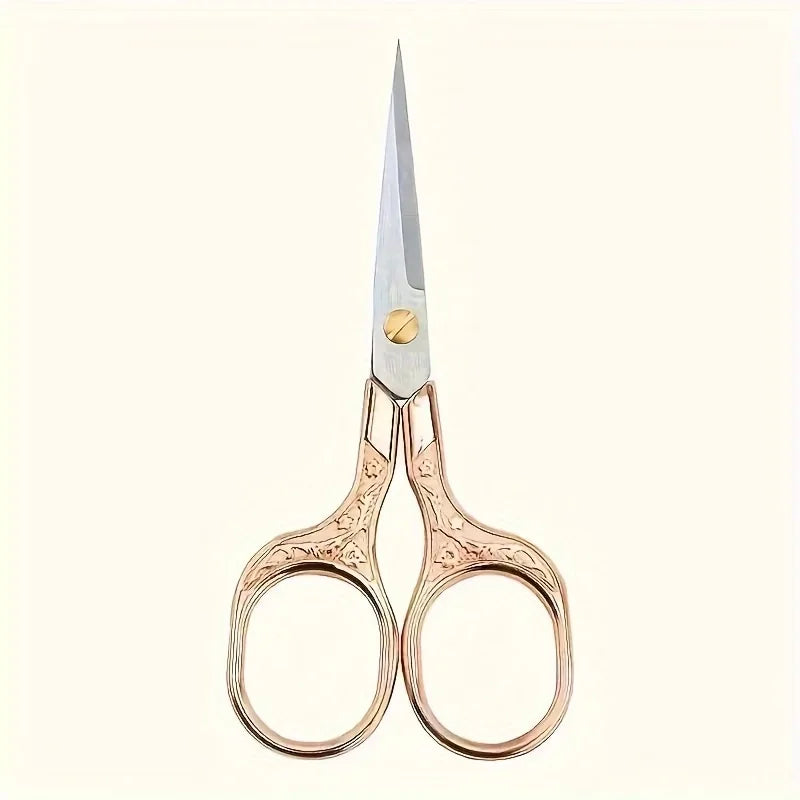 A pair of vintage stainless steel sewing scissors with rose gold handles and a silver blade.