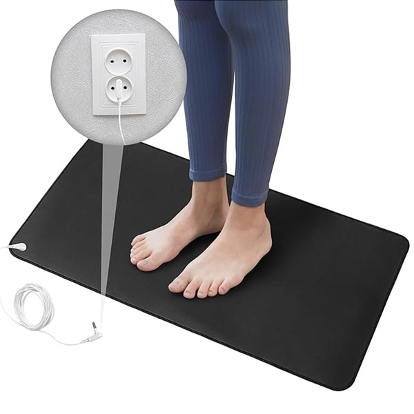 A black grounding mat with a white electrical plug and a round pad, shown next to a person's legs.