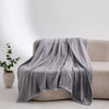 A soft gray flannel throw blanket draped over a light-colored sofa.