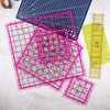 A set of acrylic quilting rulers in various sizes and a ironing ruler laid on a light gray surface.