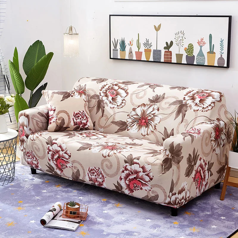 A beige floral patterned universal stretch sofa and chair slipcover displayed on a floor with a framed botanical print.
