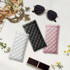 A collection of quilted PU leather eyeglass cases in black, gray, and pink, along with a pair of sunglasses and a cleaning cl