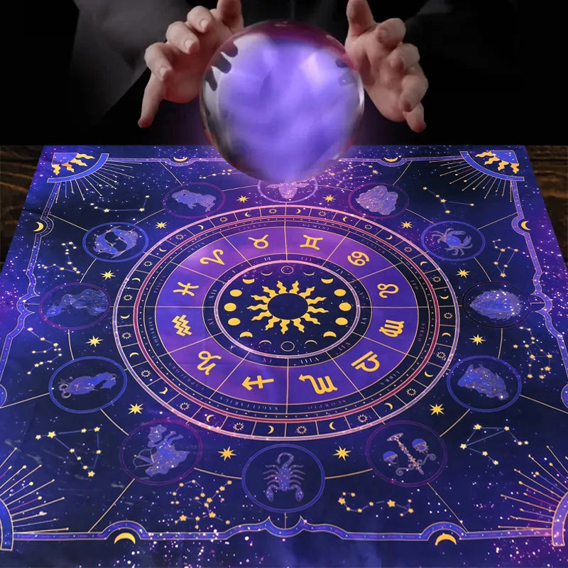 A purple tarot card tablecloth featuring astrological symbols and celestial bodies, with a glowing crystal ball above it.