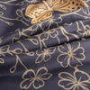 Dark blue fabric with a gold butterfly and floral print, showing the texture and drape of the material.