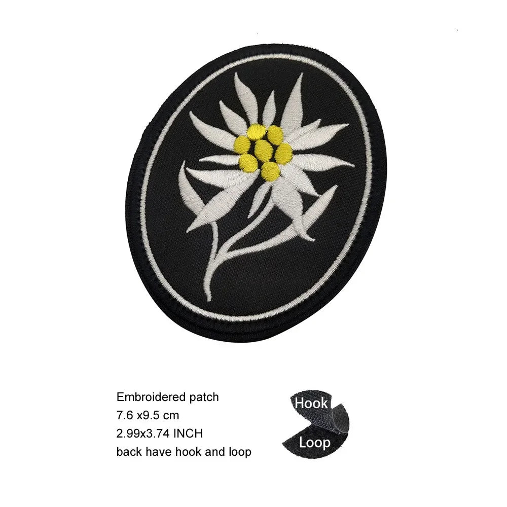 Black embroidered patch featuring a white flower with yellow center and green stem, with hook and loop backing.