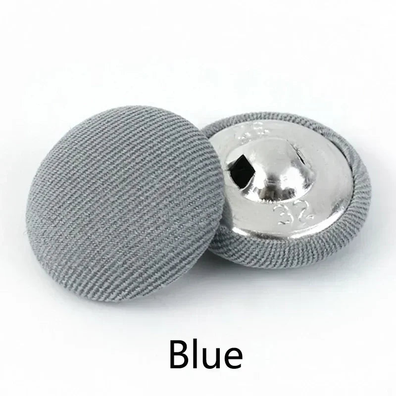 A round, gray fabric-covered shank button with a silver backing is shown.