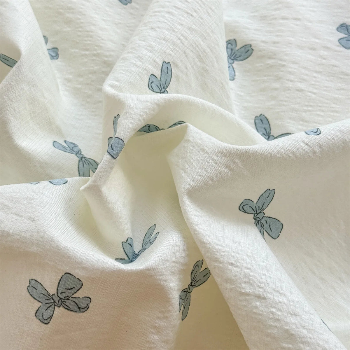 White microfiber duvet fabric with light blue floral print folded and draped.
