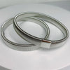 Silver metal sleeve garters or adjustable arm bands lying on a white surface.