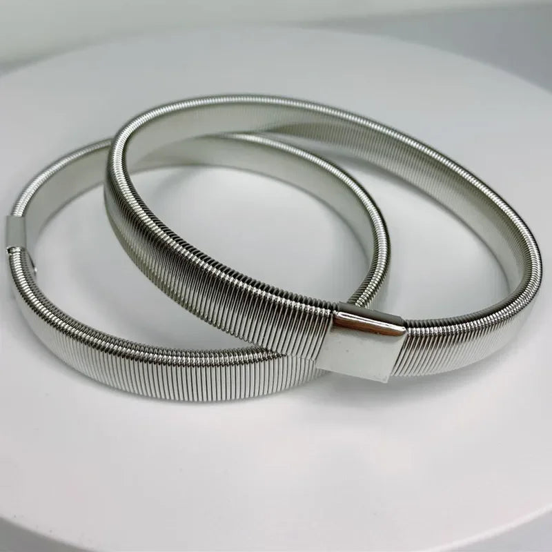 Silver metal sleeve garters or adjustable arm bands lying on a white surface.