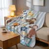 A C-Curious George plush throw blanket featuring various scenes and characters on a light blue and white striped background.