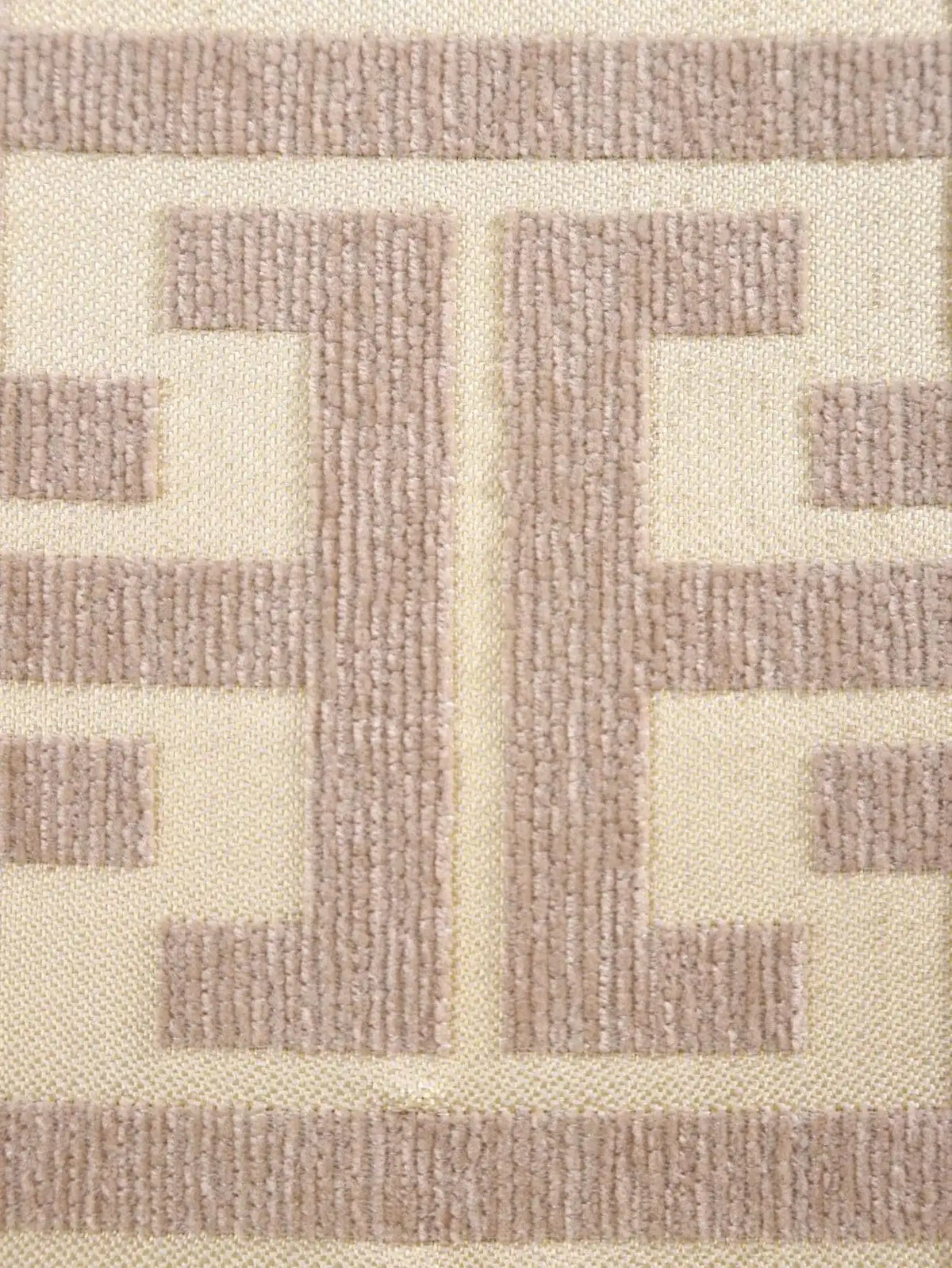 Close-up of a beige fabric featuring a geometric pattern created by light brown embroidered stitching.