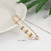 Gold-toned adjustable pearl brooch featuring a string of white pearls and small gold accents.