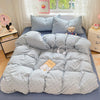 A light blue microfiber duvet cover set with matching pillowcases and a teddy bear toy on a bed.
