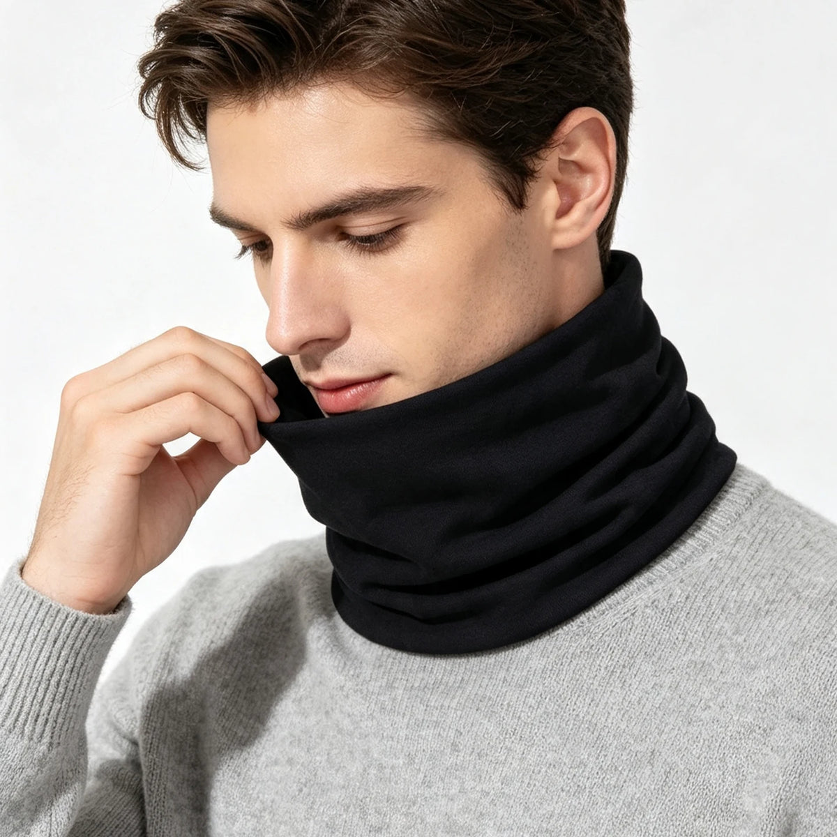 A man wearing a black soft cotton warm neck scarf over a gray sweater.