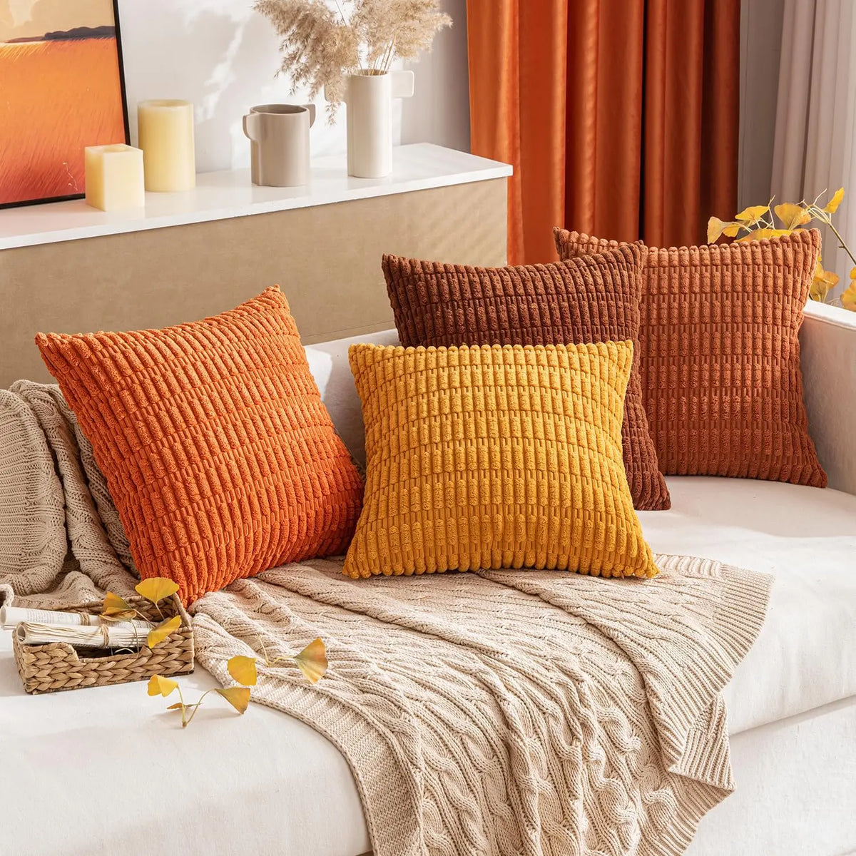 A collection of textured, woven throw pillows in shades of orange, mustard yellow, and terracotta on a light sofa.