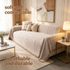 A beige chenille sofa protector featuring a fishbone pattern draped over a light-colored sofa in a bright, modern room.