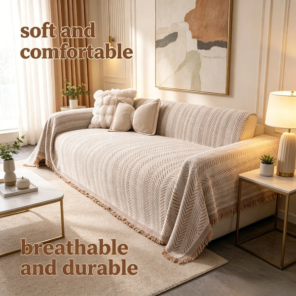 A beige chenille sofa protector featuring a fishbone pattern draped over a light-colored sofa in a bright, modern room.