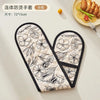 A pair of floral patterned heat-resistant oven mitts with a black trim are displayed on a white surface.