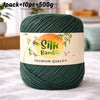 A skein of dark green silk bamboo blend yarn is shown on a white surface.