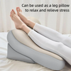 A pair of feet resting on a gray ergonomic memory foam pillow, suggesting relaxation and stress relief.