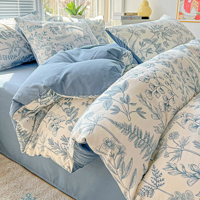 A set of light blue and white floral printed bedding, including pillows and a duvet, displayed on a bed.