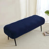 A navy blue elastic jacquard bench cover placed on a light carpet in a bright room.