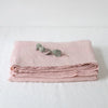 Pink pure French linen bed sheet folded neatly on a white surface.