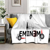 A white throw blanket featuring a black and red graphic of Eminem's face and name.