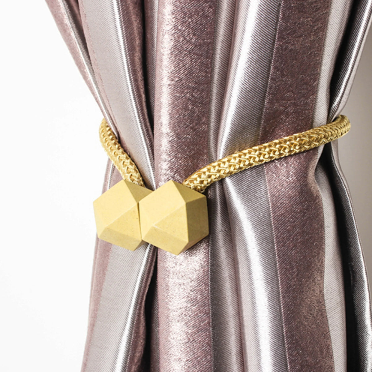 Gold chain tiebacks with hexagonal magnetic clasps securing a mauve satin curtain.
