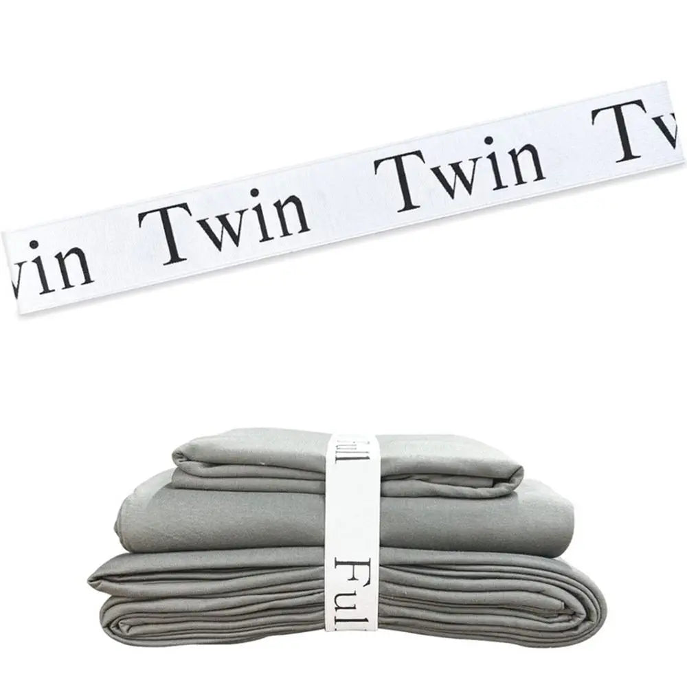 Gray bed sheets neatly folded and stacked with white organizer straps.