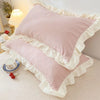 Pink ruffled pillowcases with a white trim and hidden zipper displayed on a light-colored surface.