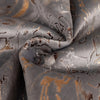 Close-up of a dark gray velvet fabric with gold foil leaf pattern, folded and draped.