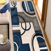 A geometric patchwork floor mat featuring shades of blue, gray, and cream patterns.