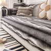 Gray plush velvet sofa protector covers draped over a white sofa with beige cushions.