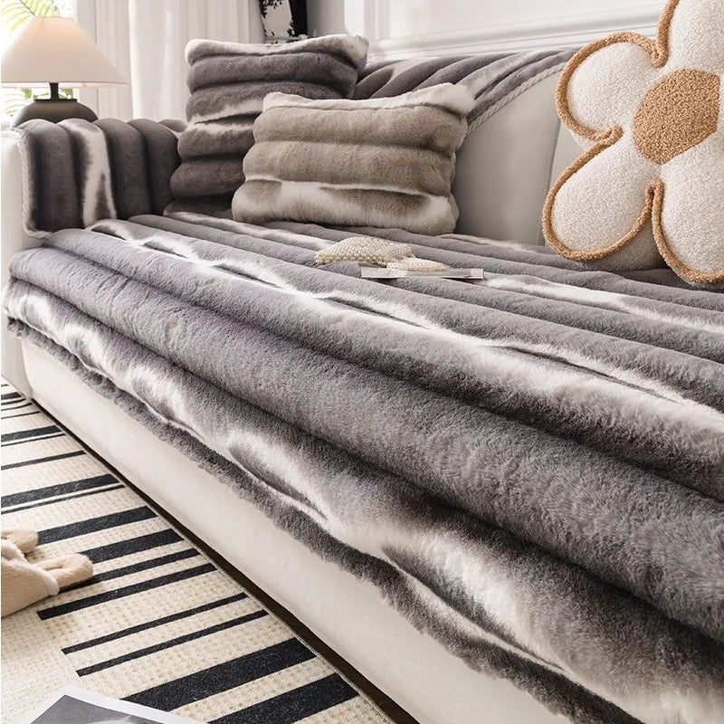 Gray plush velvet sofa protector covers draped over a white sofa with beige cushions.