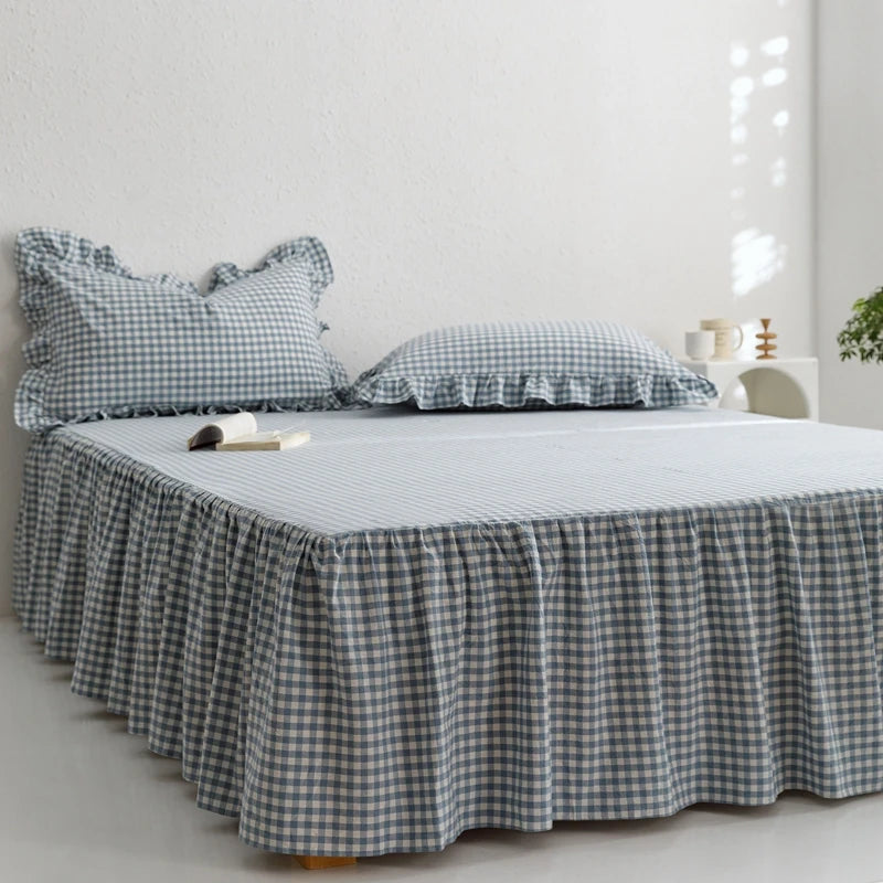 A plaid cotton bed skirt cover in blue and white checks draped over a bed.