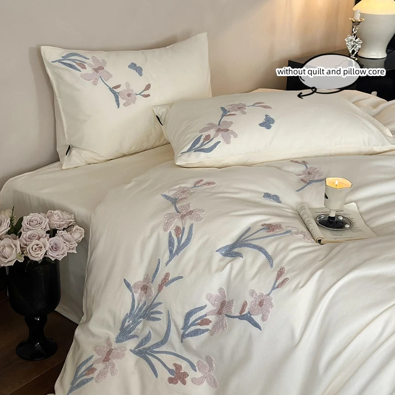 White embroidered orchid duvet cover set with lace trim displayed on a bed.