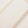 A beige soft plush mattress and diaper changing cover with a textured fabric and decorative stitching.