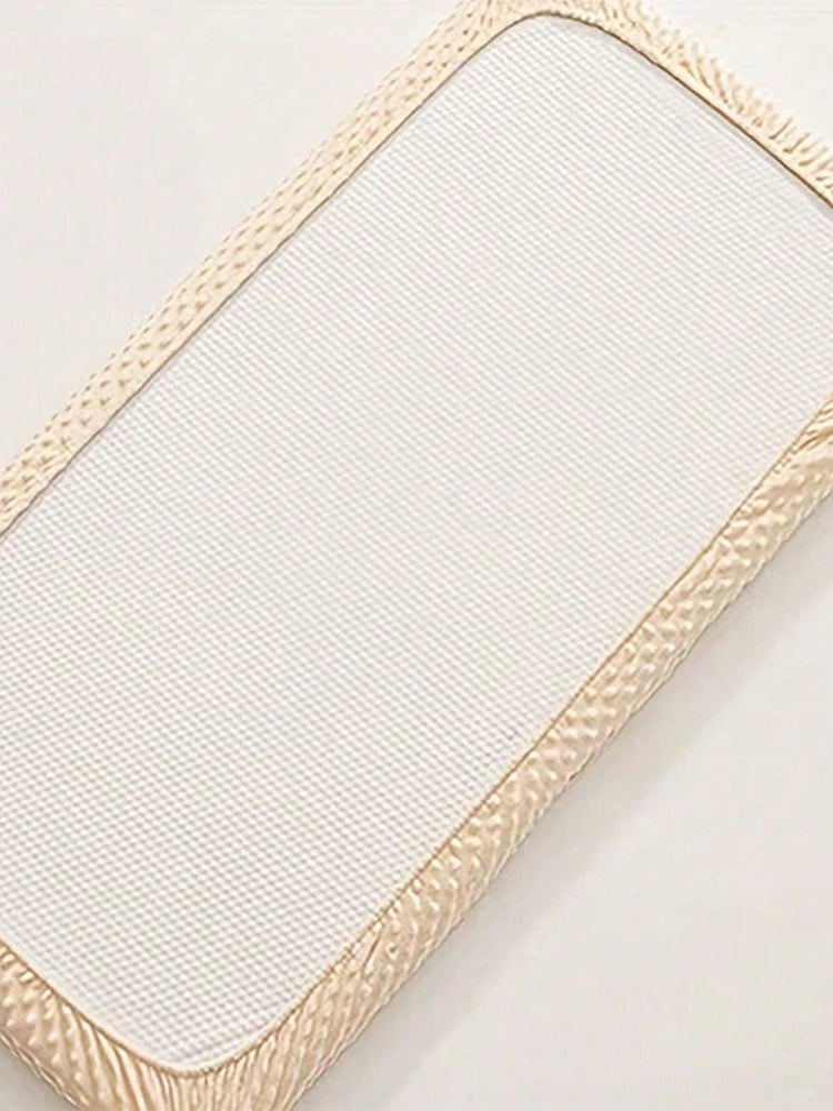 A beige soft plush mattress and diaper changing cover with a textured fabric and decorative stitching.