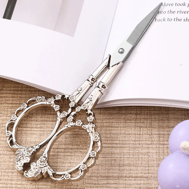A pair of silver crafting scissors resting on a light-colored notebook or paper.