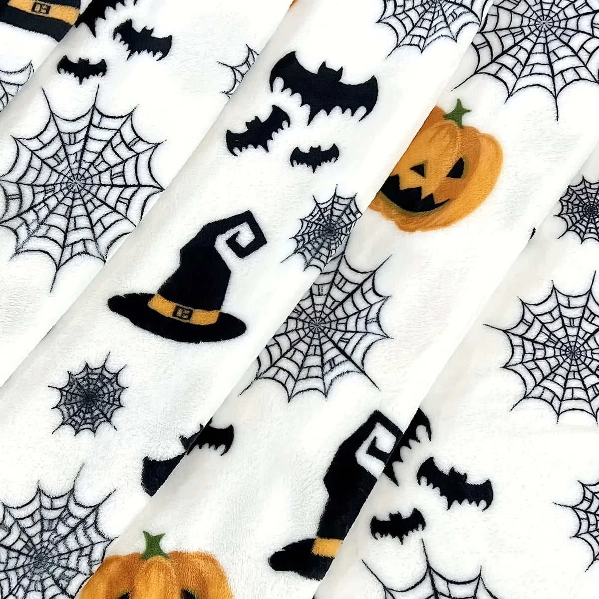 White flannel blanket featuring a Halloween theme with black bats, spider webs, and a pumpkin.