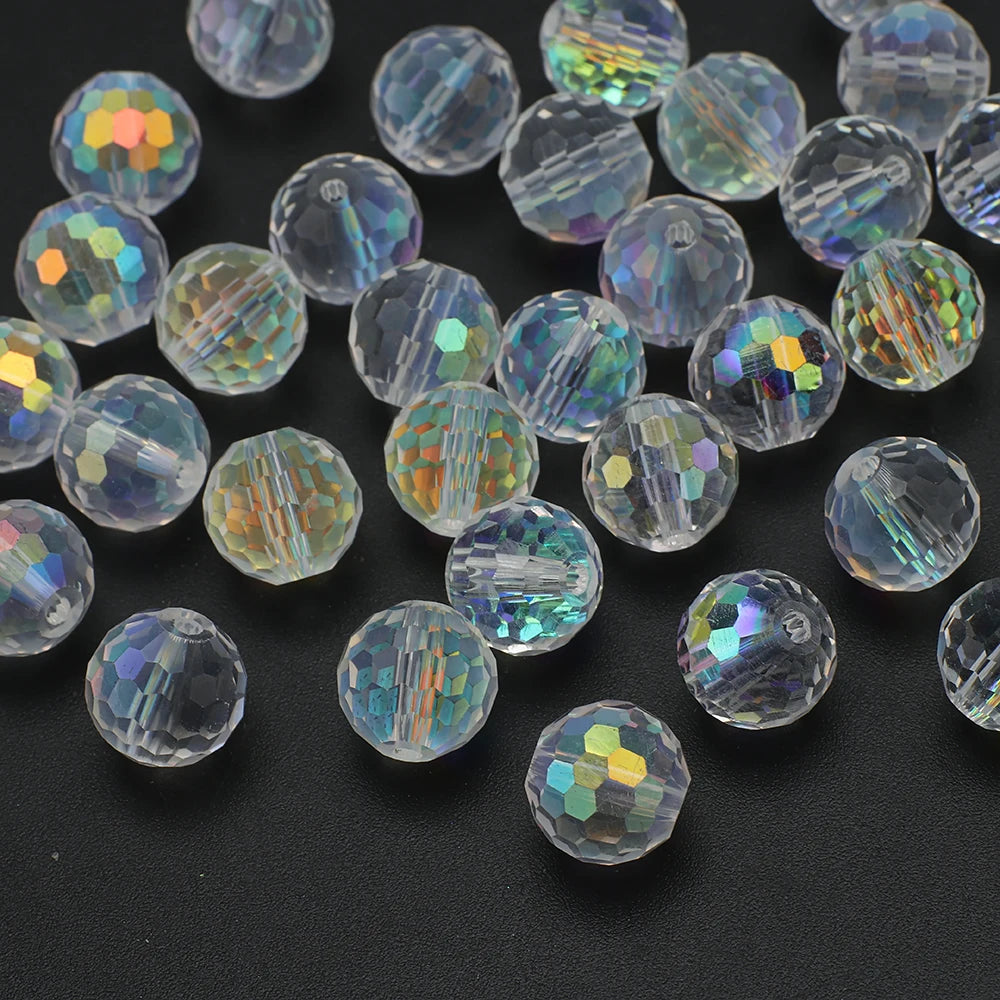 A collection of multi-size shiny AB crystal glass beads with facets scattered on a dark surface.