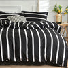 Black and white striped duvet cover set with pillows on a bed against a white wall.