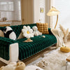 A deep emerald green plush rabbit sofa cushion resting on a light wood floor with white faux fur accents.