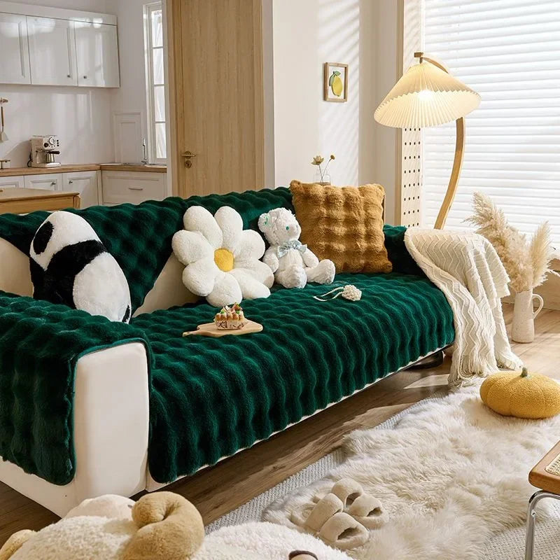 A deep emerald green plush rabbit sofa cushion resting on a light wood floor with white faux fur accents.